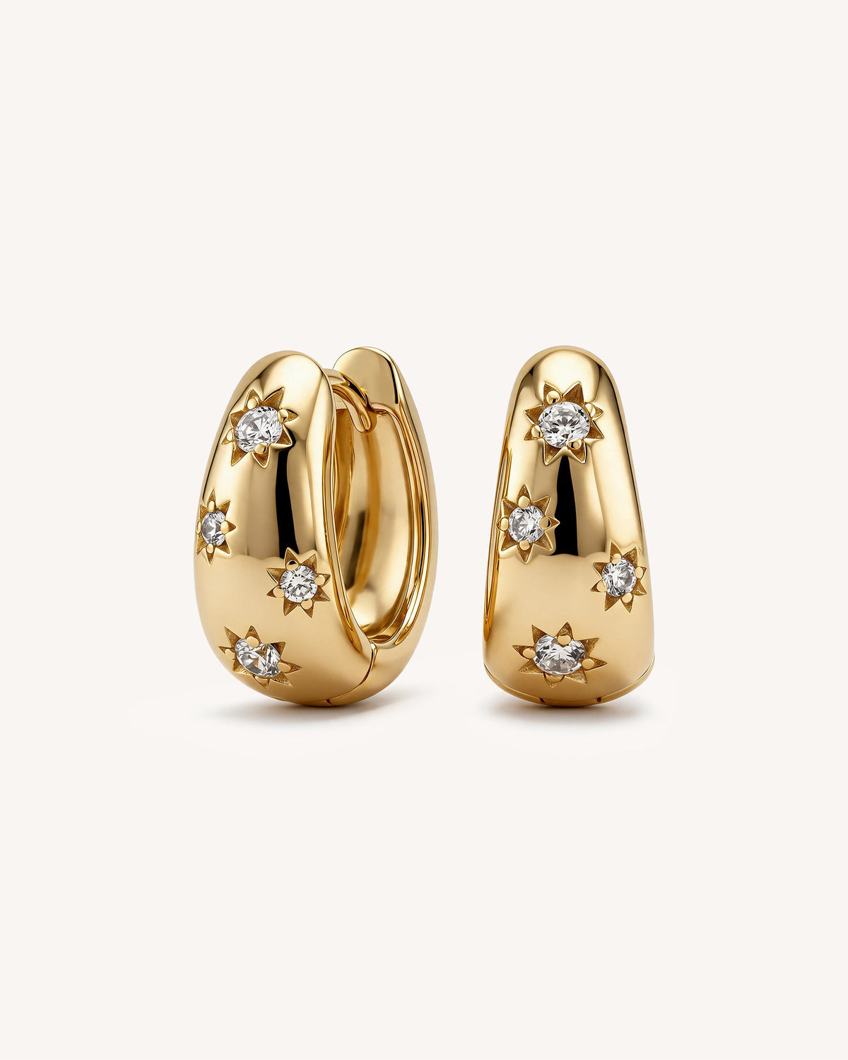 A pair of 18k gold vermeil huggie hoop earrings with star-shaped diamond accents, displayed on a clean off-white background.