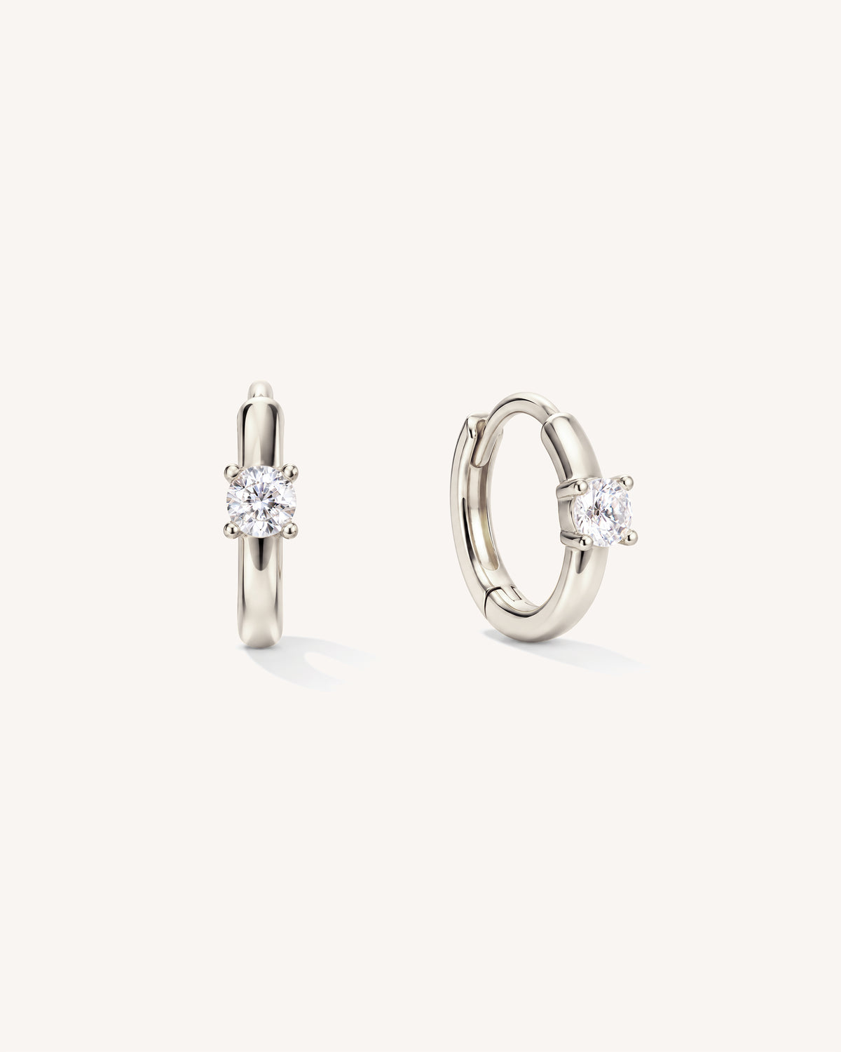 Classic small hoop huggie earrings with a solitaire against a minimal white background.