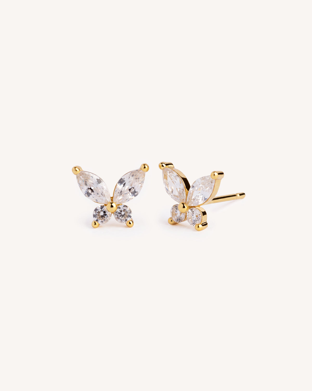 A pair of gold butterfly stud earrings with marquise-cut clear crystals, shown on a plain off-white background.