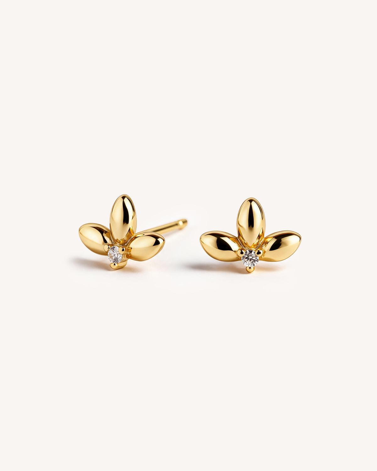 A pair of 18k gold plated three petal flower like stud earrings with a small clear CZ stone.