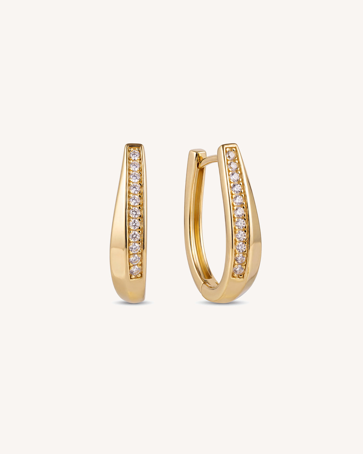 A pair of gold hoop earrings with a channel-set row of clear cz pave stones on the front, shown against a plain off-white background.