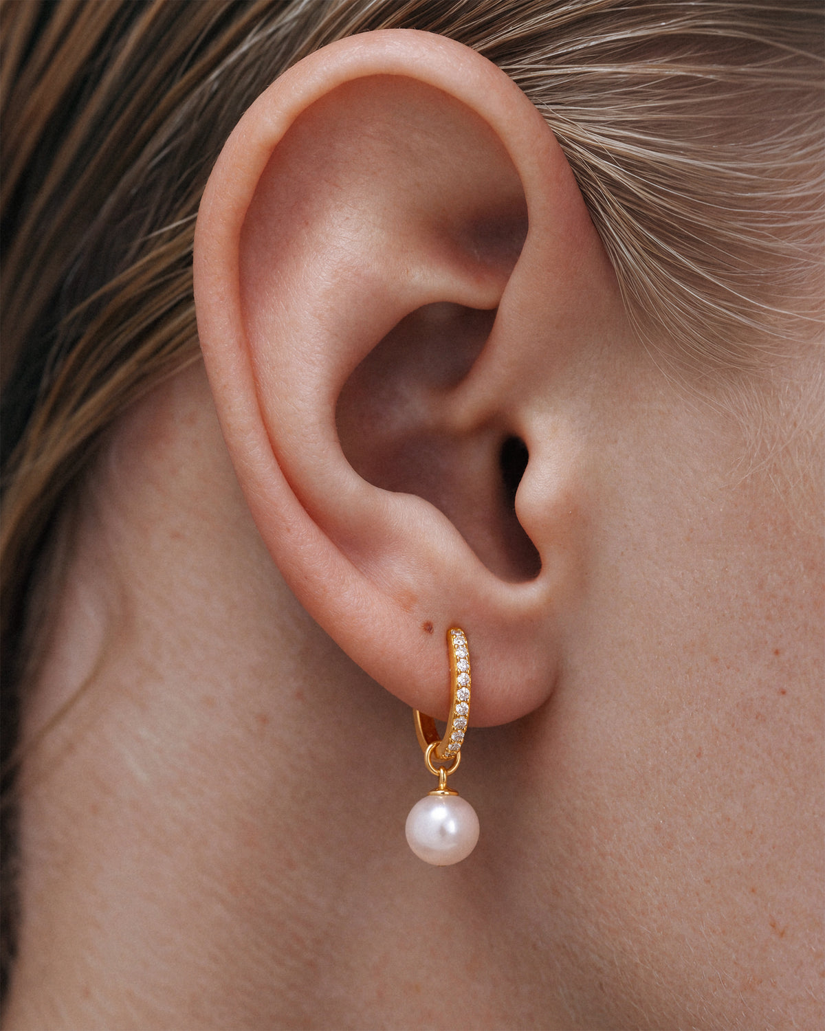 Gold pavé huggie hoop earring with pearl drop charm, 18k gold-plated sterling silver, worn on the ear