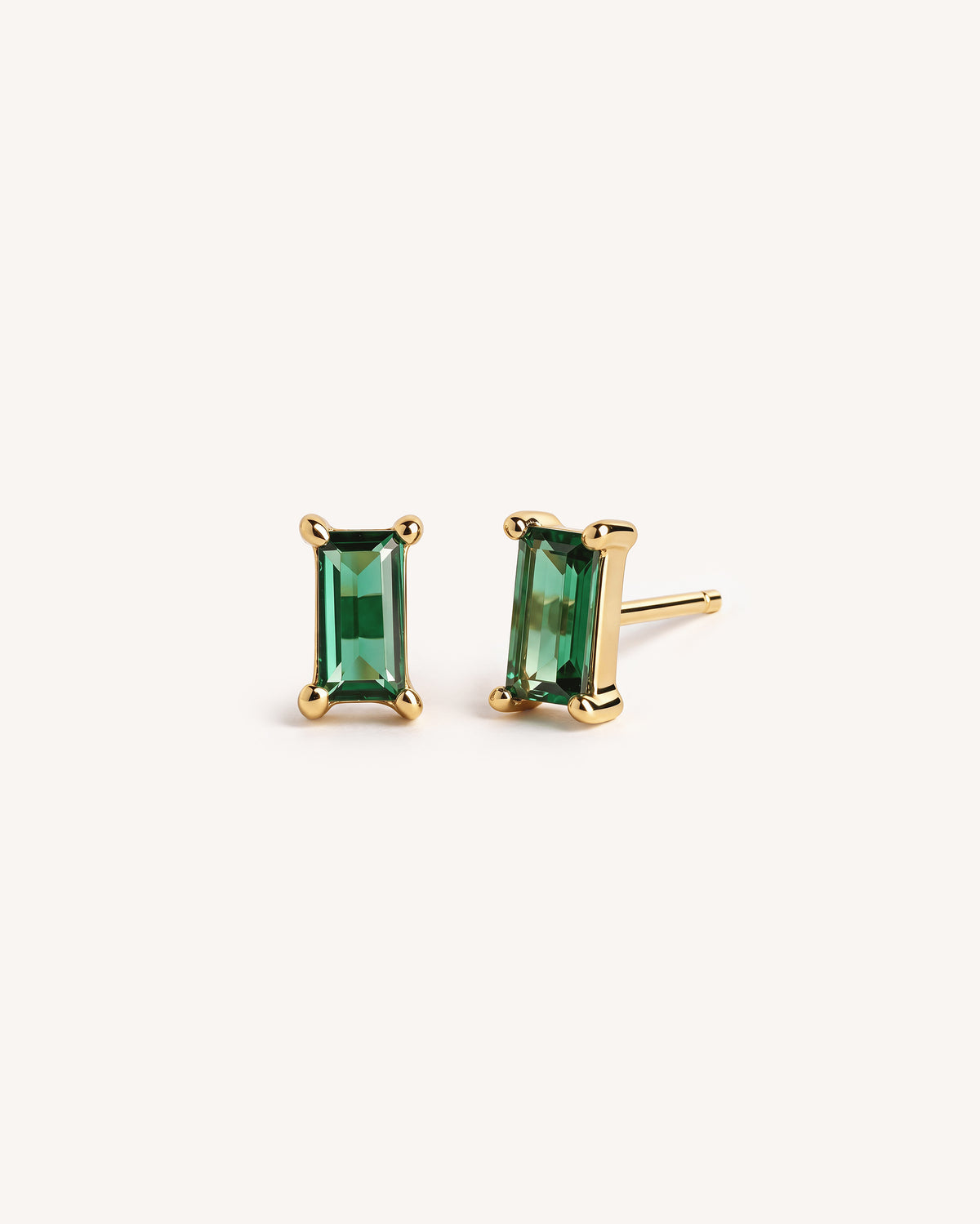 Baguette Solitaire studs with an emerald stone on a plain white background.