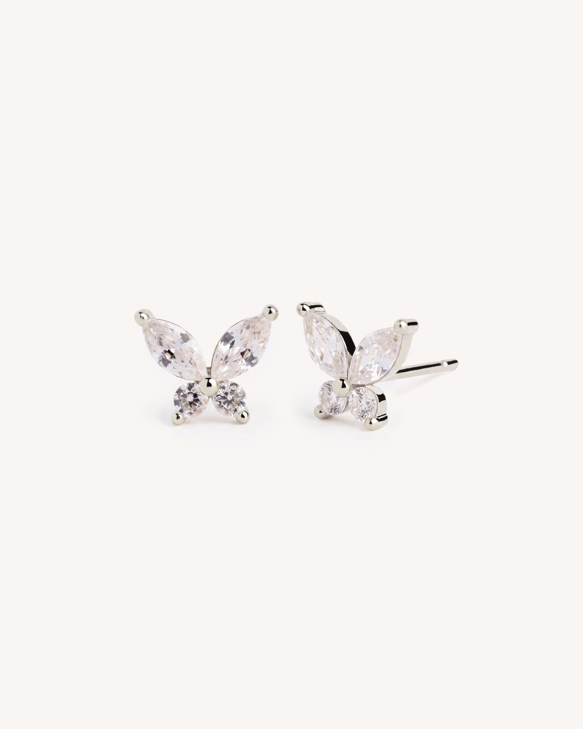 A pair of silver butterfly stud earrings with marquise-cut clear crystals, shown on a plain off-white background.