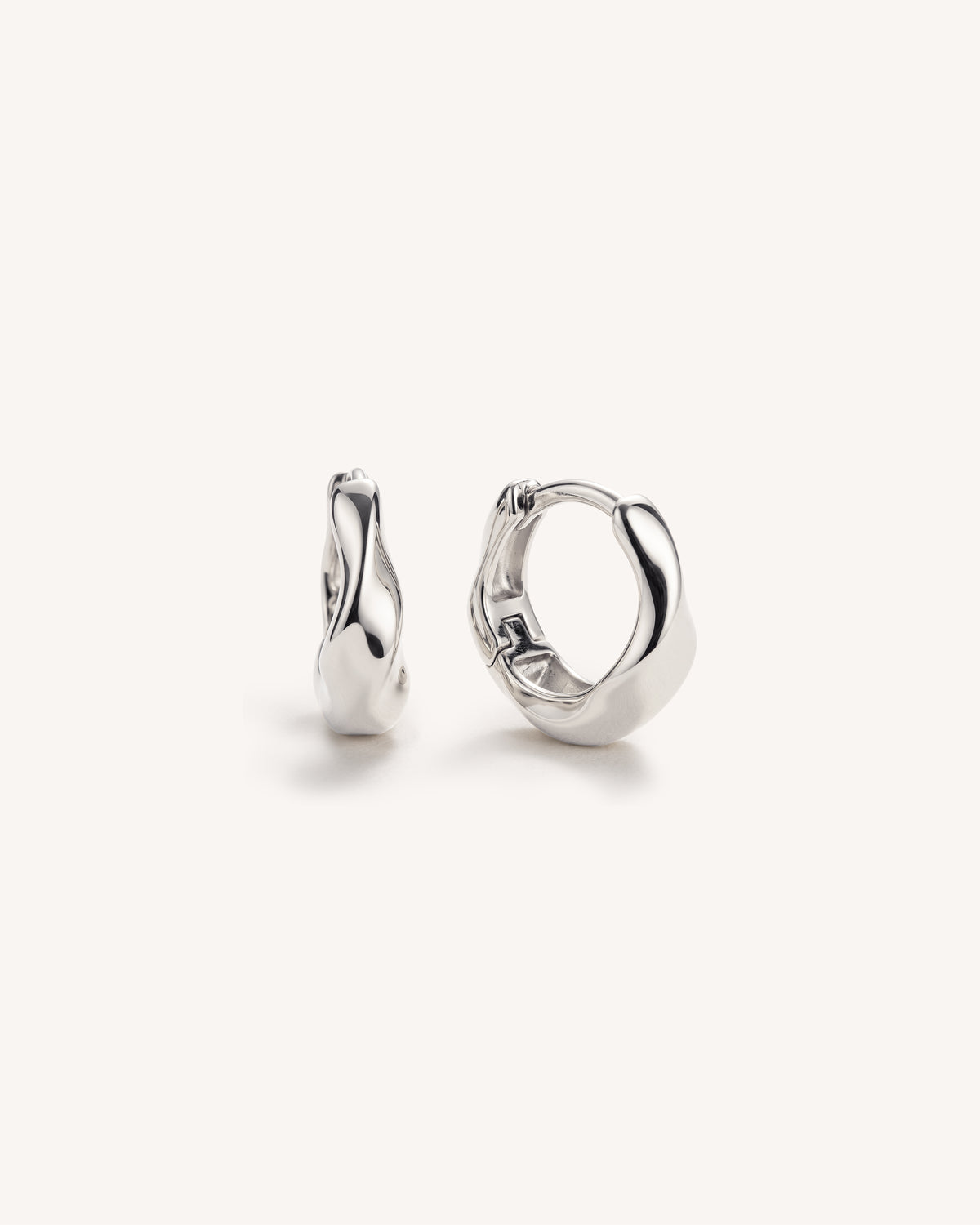 A pair of polished 925 sterling silver huggie hoop earrings with a fluid, organic wavy design, shown on a clean off-white background.