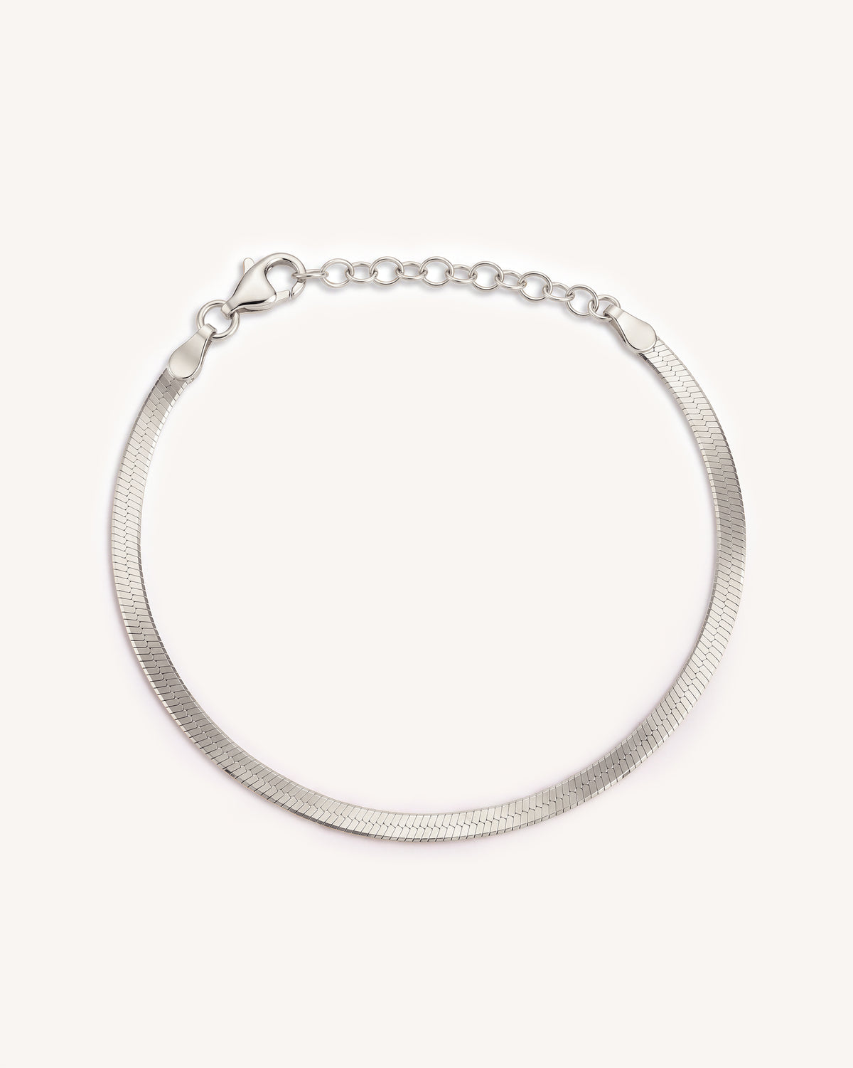 A silver-toned snake chain bracelet with a herringbone pattern and a lobster clasp and extension chain, displayed on a clean off-white background.