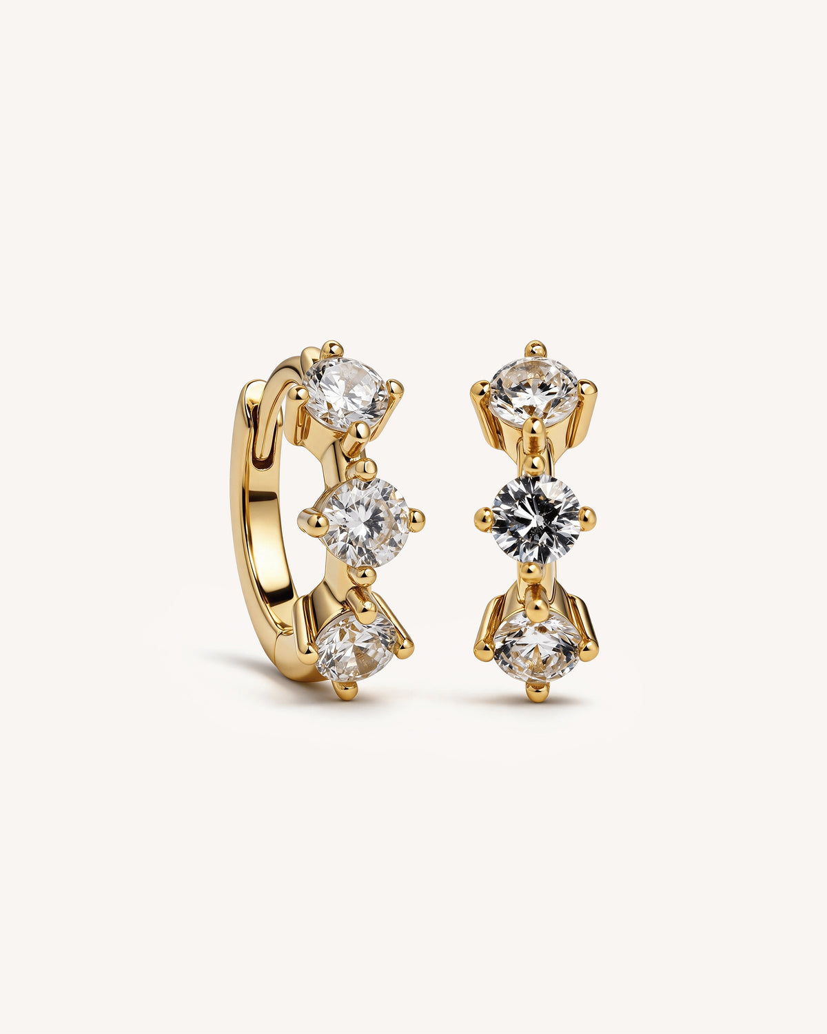 A pair of 18k gold plated vermeil huggie hoop earrings with clear round-cut gemstones, displayed on a clean off-white background.