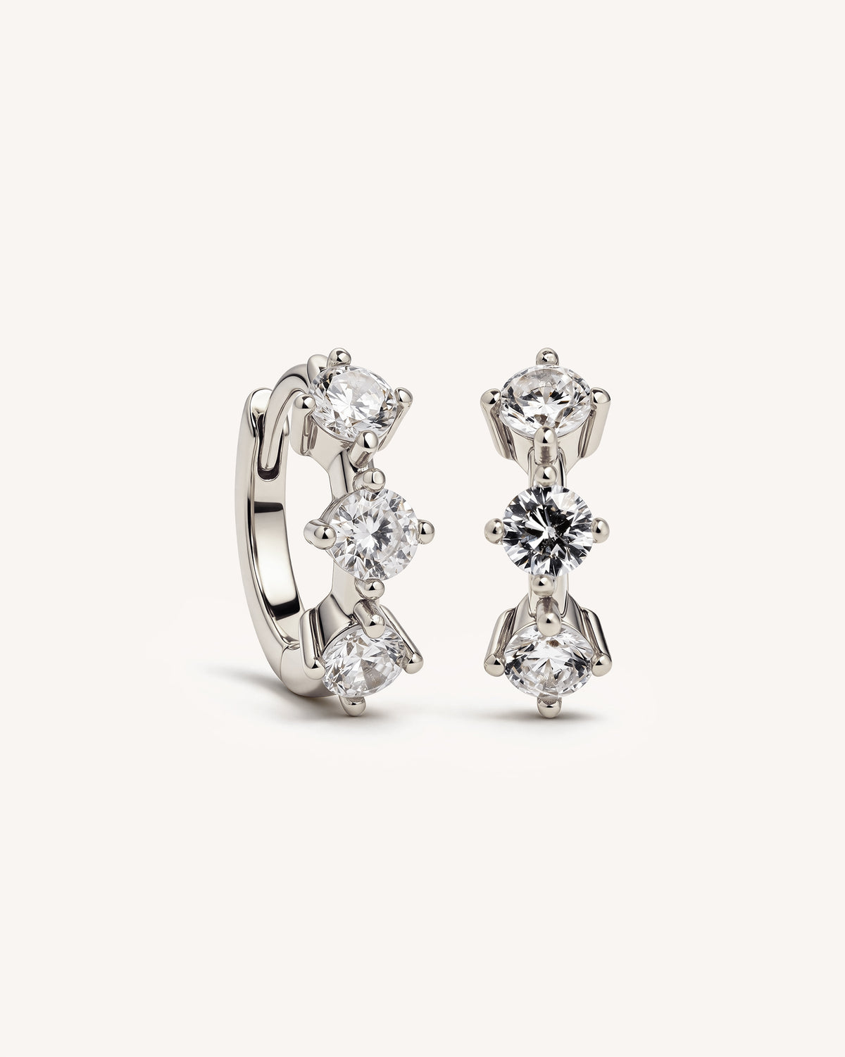 A pair of 925 sterling silver huggie hoop earrings with clear gemstones, displayed on a clean off-white background.