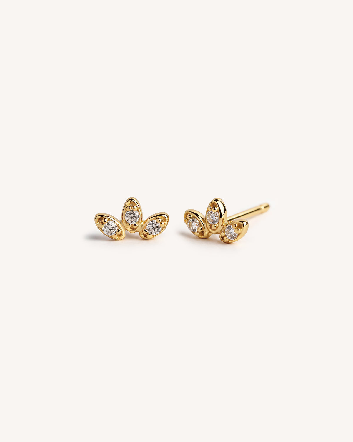 A pair of 18k gold plated 925 sterling silver stud earrings with marquise-cut clear gemstones arranged in a small leaf or cluster or petal shape, photographed on a clean off-white background.